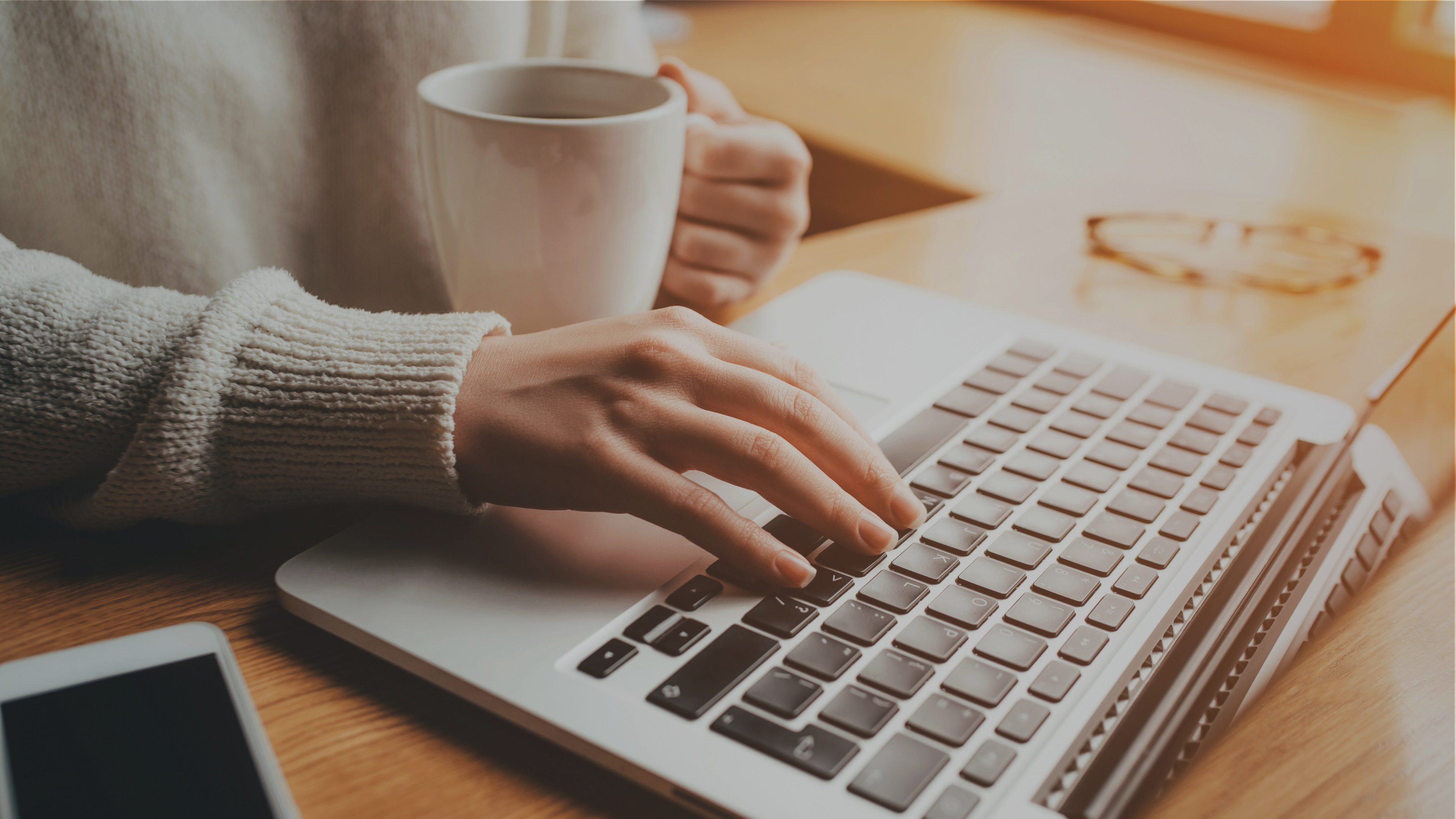 Person typing on a laptop while holding a cup, symbolising contact and easy online booking for Pablo Tymoszuk.